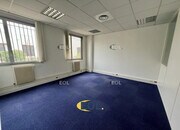 Bureau lumineux avec un sol en moquette bleue et fenêtres.