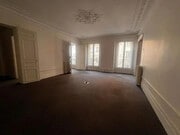 Spacieux salon lumineux avec moulures élégantes et balcon.